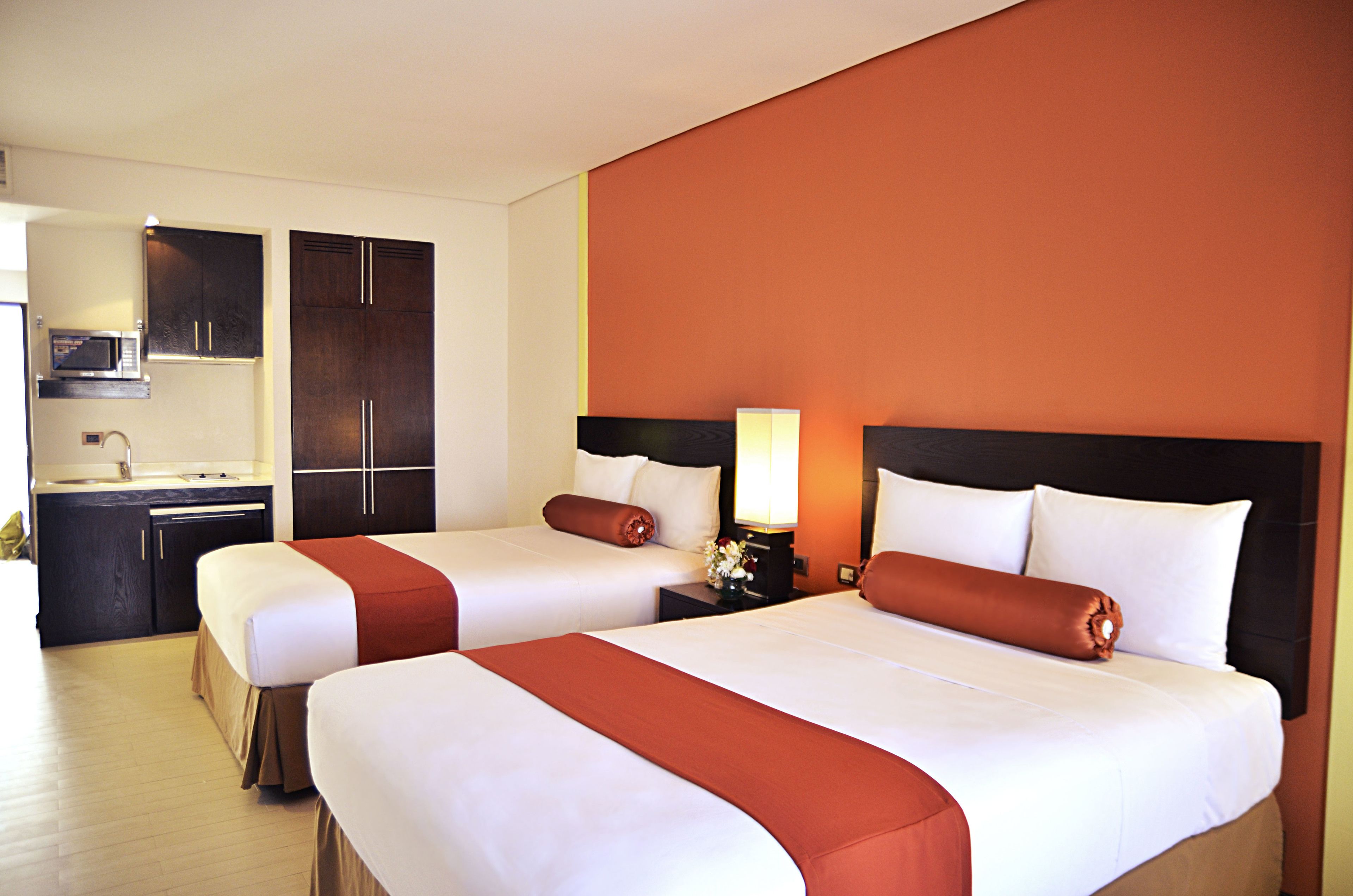 Ein Hotelzimmer mit zwei Betten, einer Küchenzeile und einem großen Spiegel.