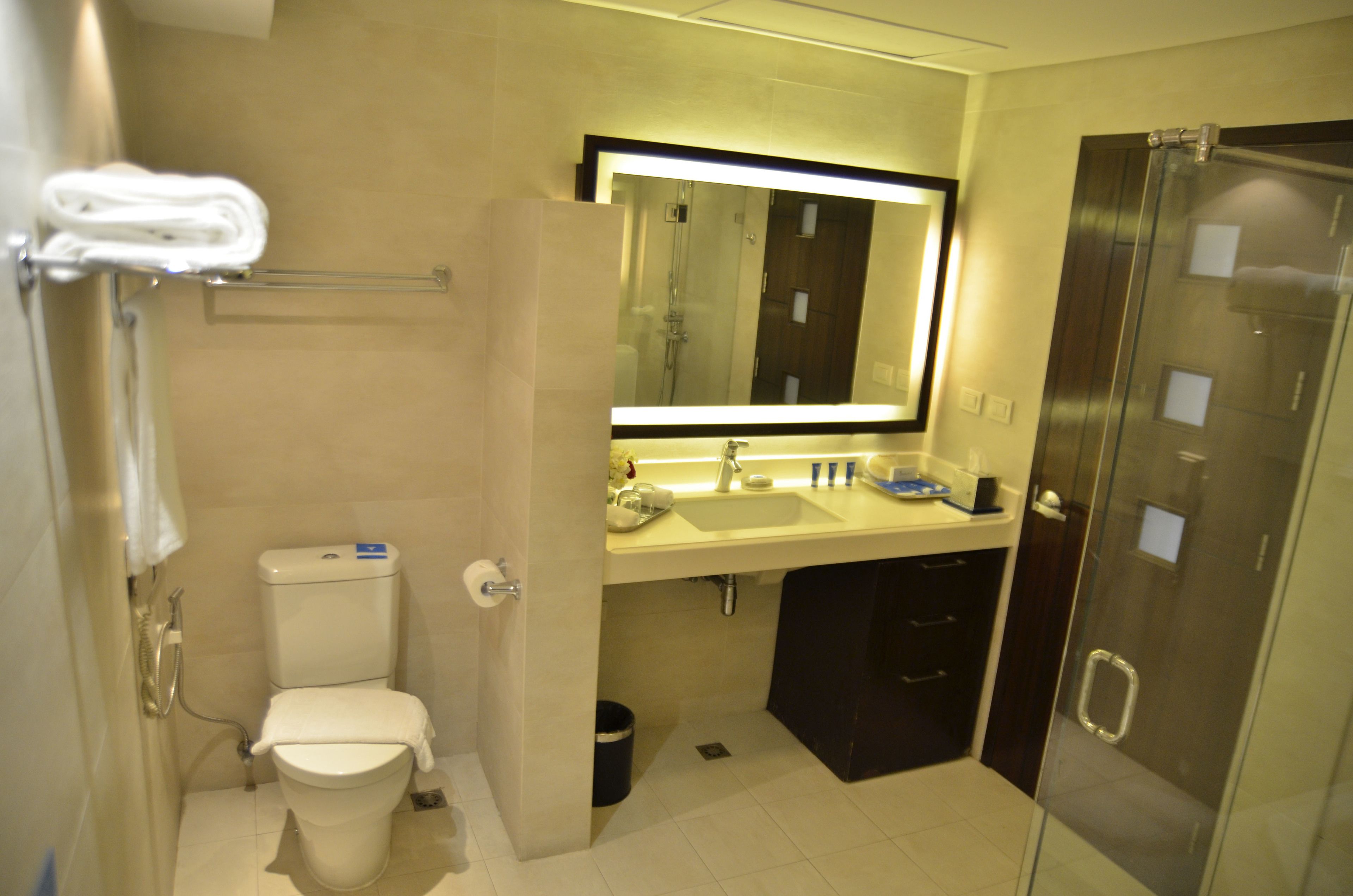 Un baño moderno con inodoro, lavamanos y cabina de ducha de vidrio.
