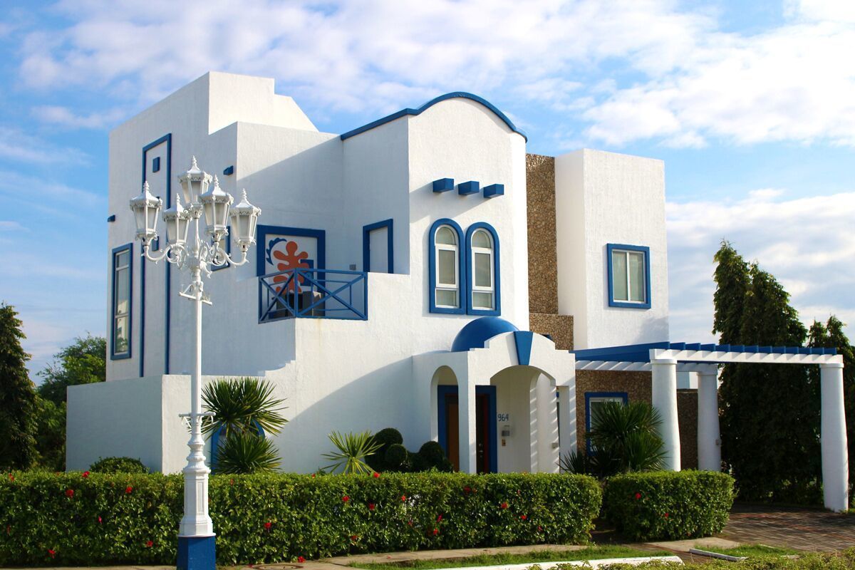 Un bâtiment moderne à la façade blanche et aux touches de bleu, doté d’une grande entrée en arc de cercle et d’un lampadaire décoratif blanc.