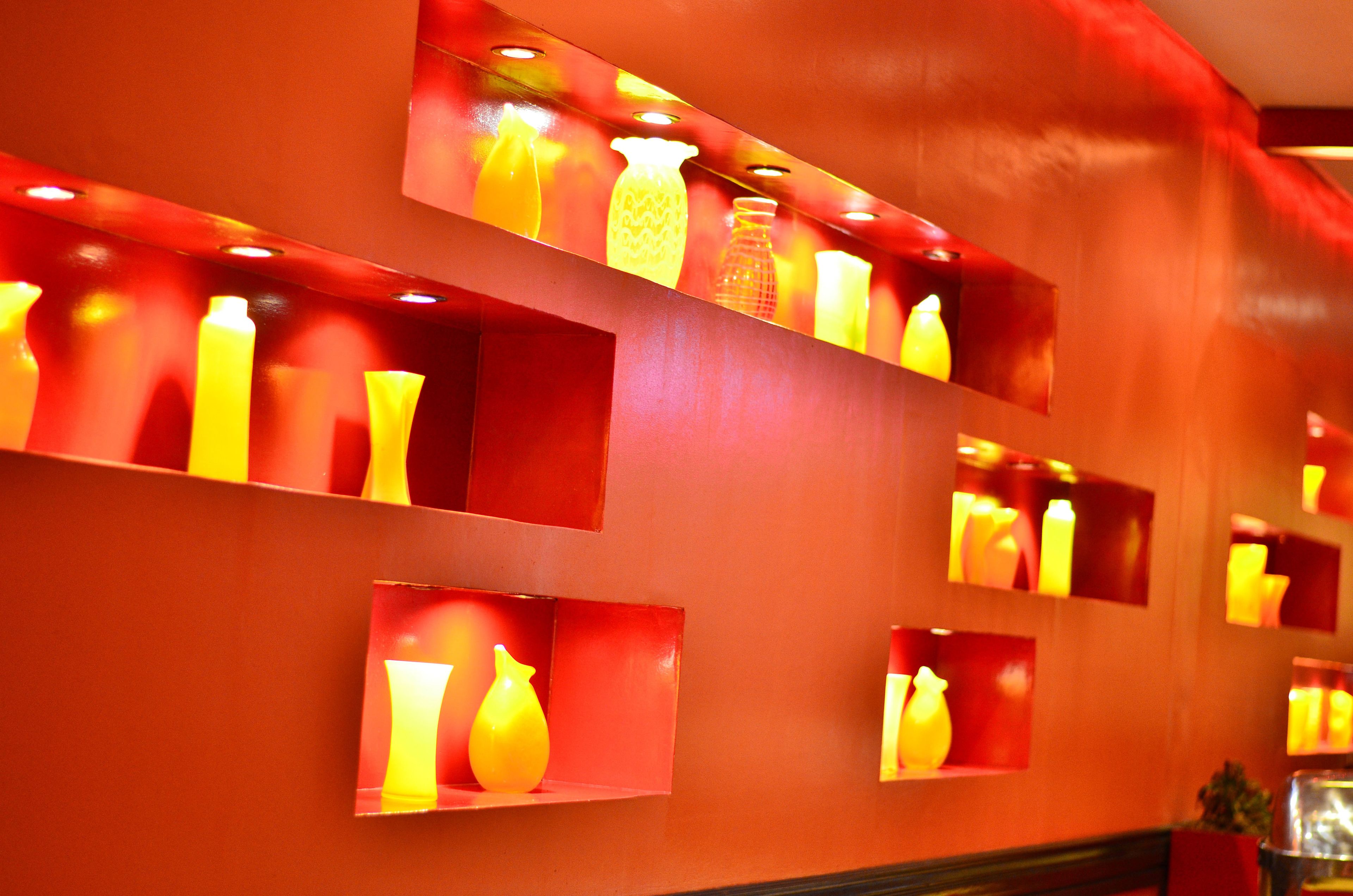 A wall with multiple illuminated shelves displaying various glassware.
