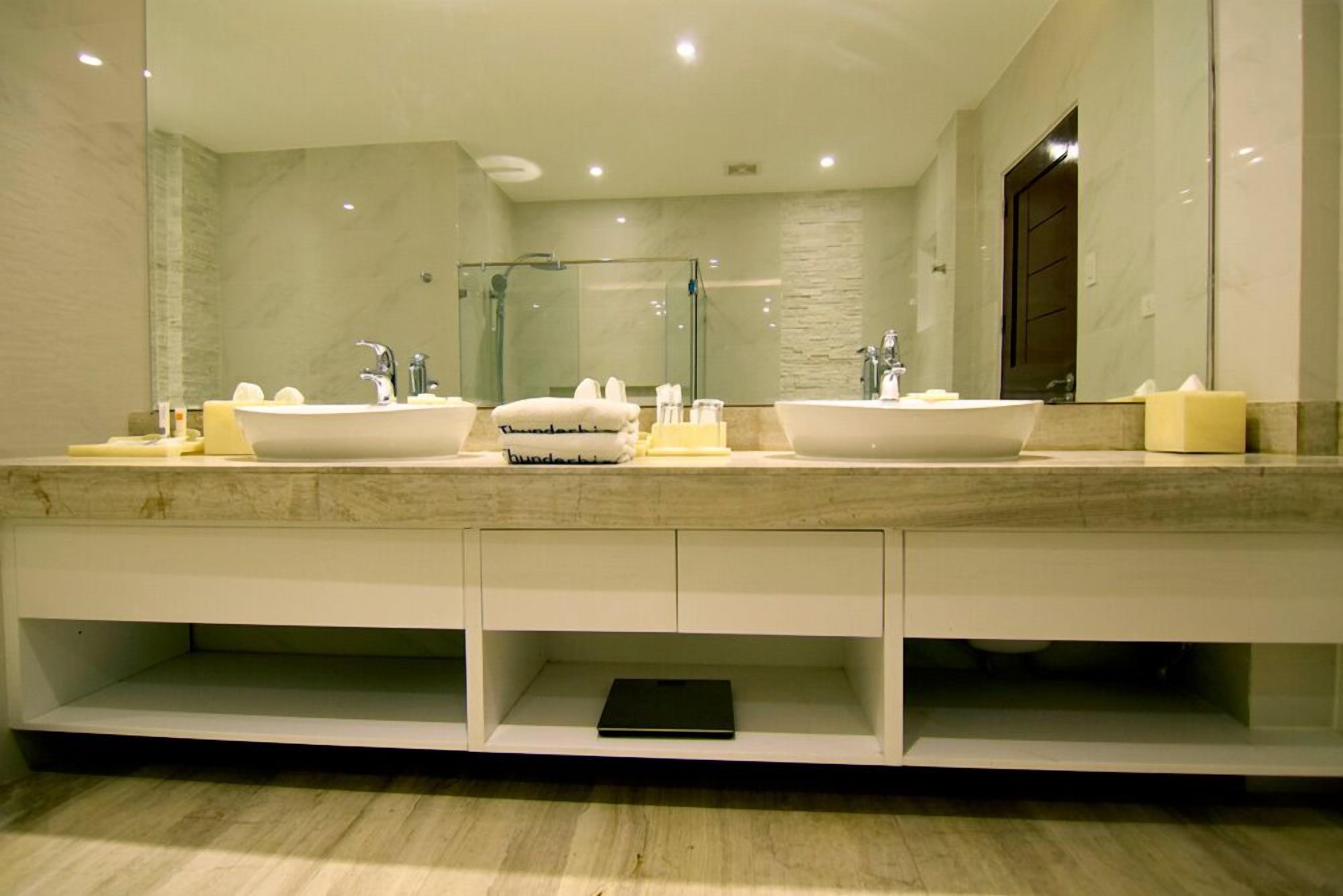 A modern bathroom with two sinks, a glass shower enclosure, and a large mirror.