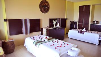Relax in a romantic retreat with two single beds, a dresser, and a large mirror.