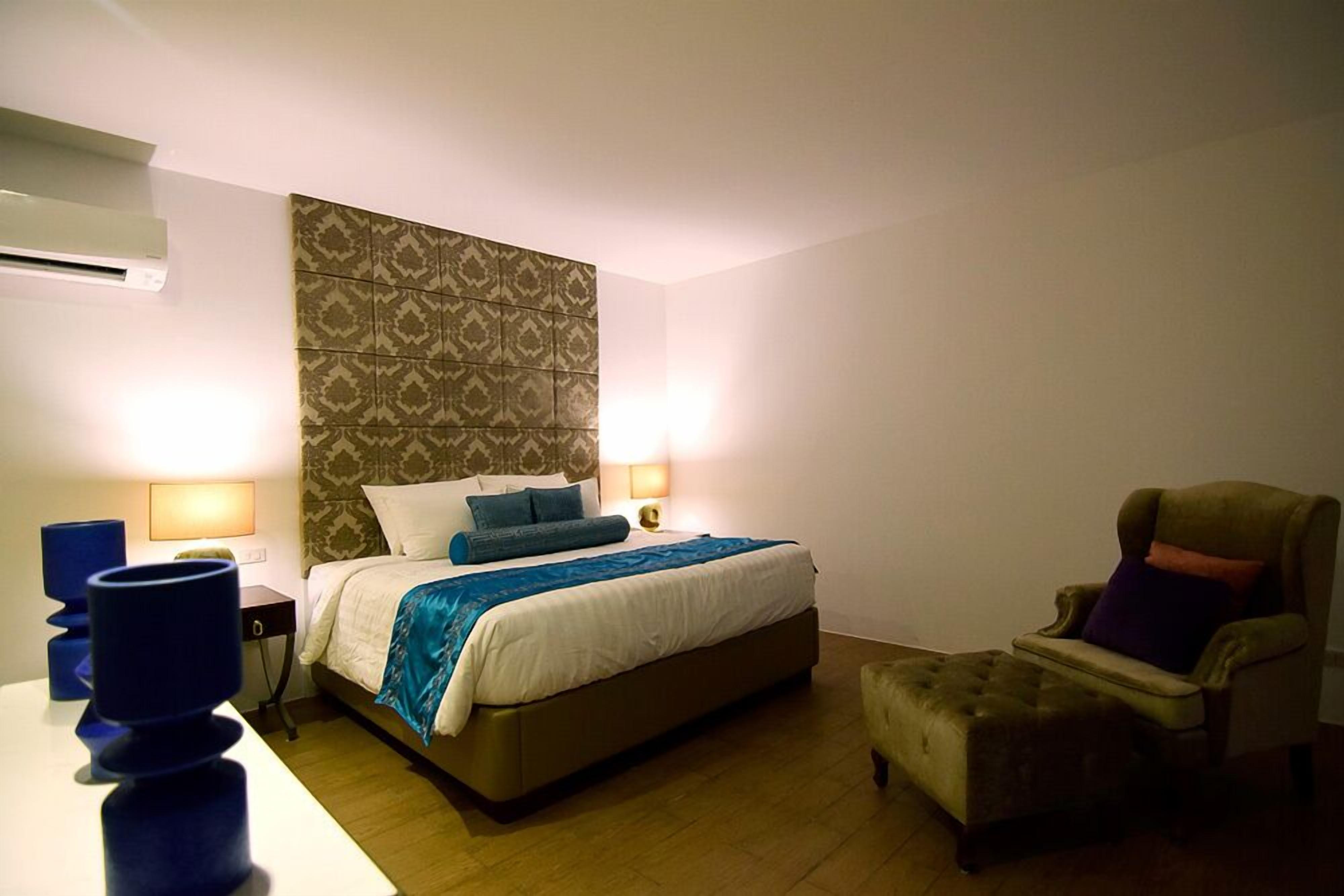 Une chambre d’hôtel avec un lit, deux lampes de chevet, une chaise et une petite table.