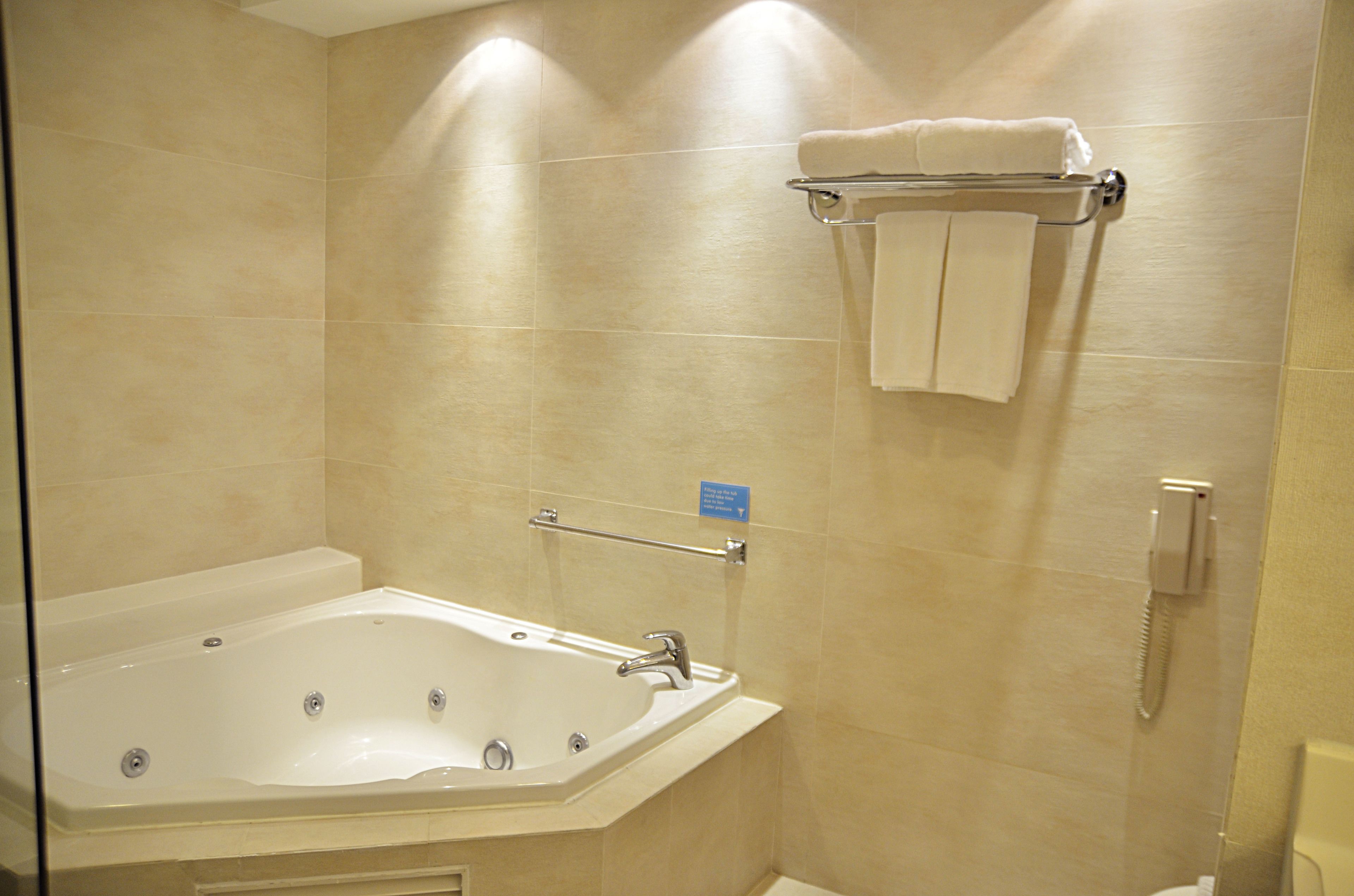 Un bagno con una vasca da bagno ampia, un portascopino con asciugamani, un asciugamani ad aria e un telefono.