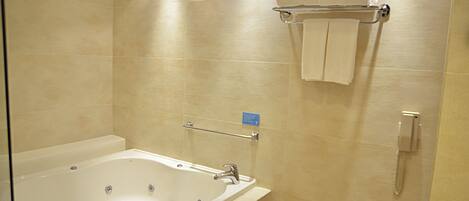 Un bagno con una vasca da bagno ampia, un portascopino con asciugamani, un asciugamani ad aria e un telefono.