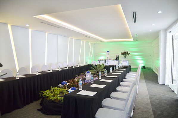 A conference room with a long table, chairs, and a stage area.