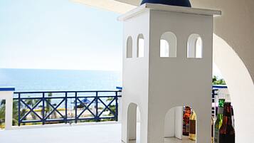 A white structure with arched openings, possibly a small kiosk or booth, on a balcony with a view of the sea.