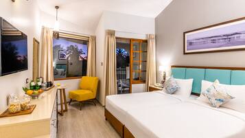 Une chambre d’hôtel avec un lit, un bureau, une chaise, une télévision et une fenêtre avec des rideaux.