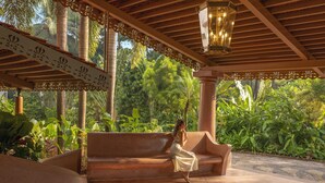 A covered outdoor seating area with a bench, a hanging lantern, and lush greenery in the background. - Heritage Village Resort & Spa Goa (Cansaulim)