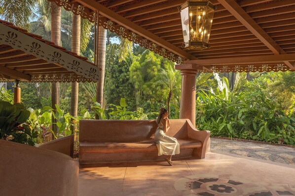 A covered outdoor seating area with a bench, a hanging lantern, and lush greenery in the background. - Heritage Village Resort & Spa Goa (Cansaulim)
