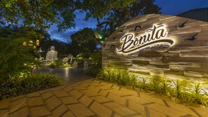 A stone sign with the name "Boruta" and the phrase "Tropical Life" illuminated at night, surrounded by greenery and a paved walkway. - Heritage Village Resort & Spa Goa (Cansaulim)