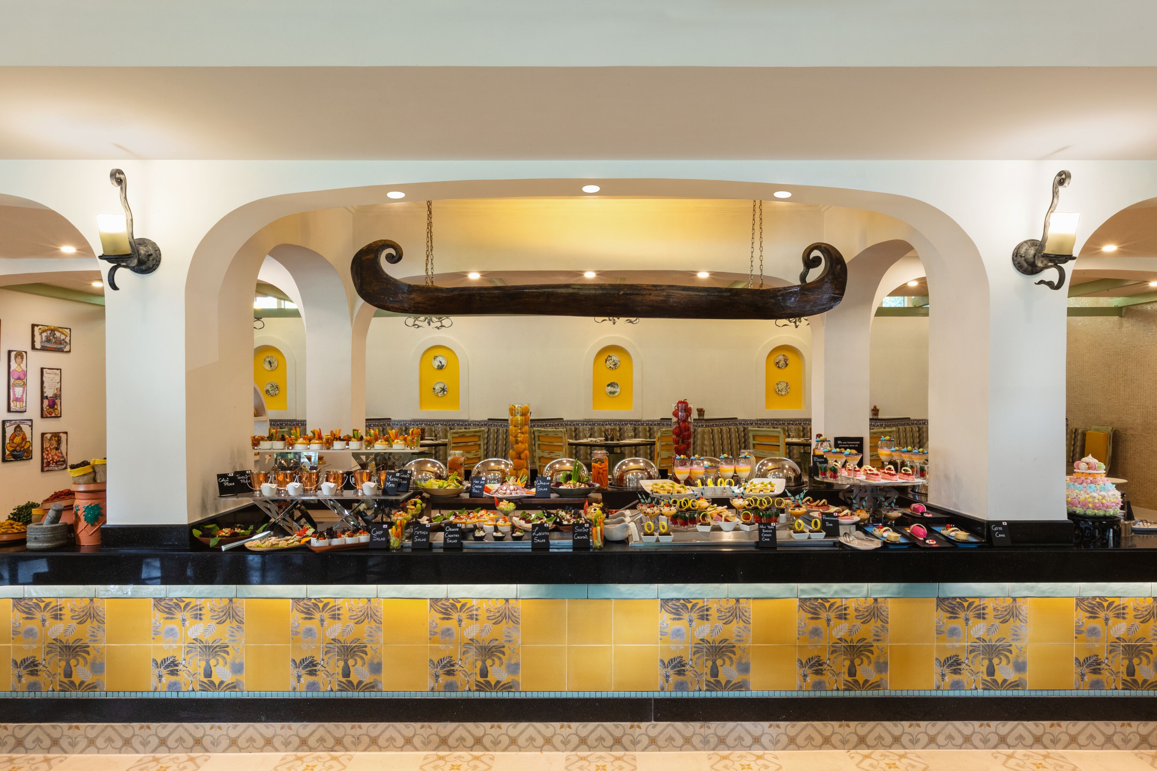 A buffet area with a variety of food items, a decorative ceiling, and a tiled backsplash.