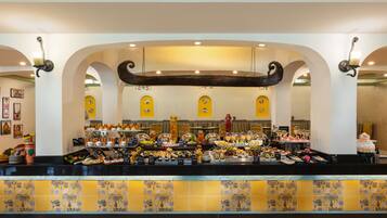 A buffet area with a variety of food items, a decorative ceiling, and a tiled backsplash.
