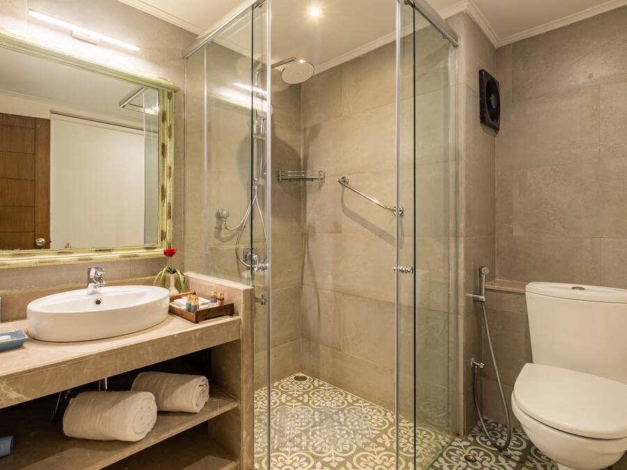 Un baño moderno con ducha envuelta en vidrio, un lavabo blanco y un inodoro.