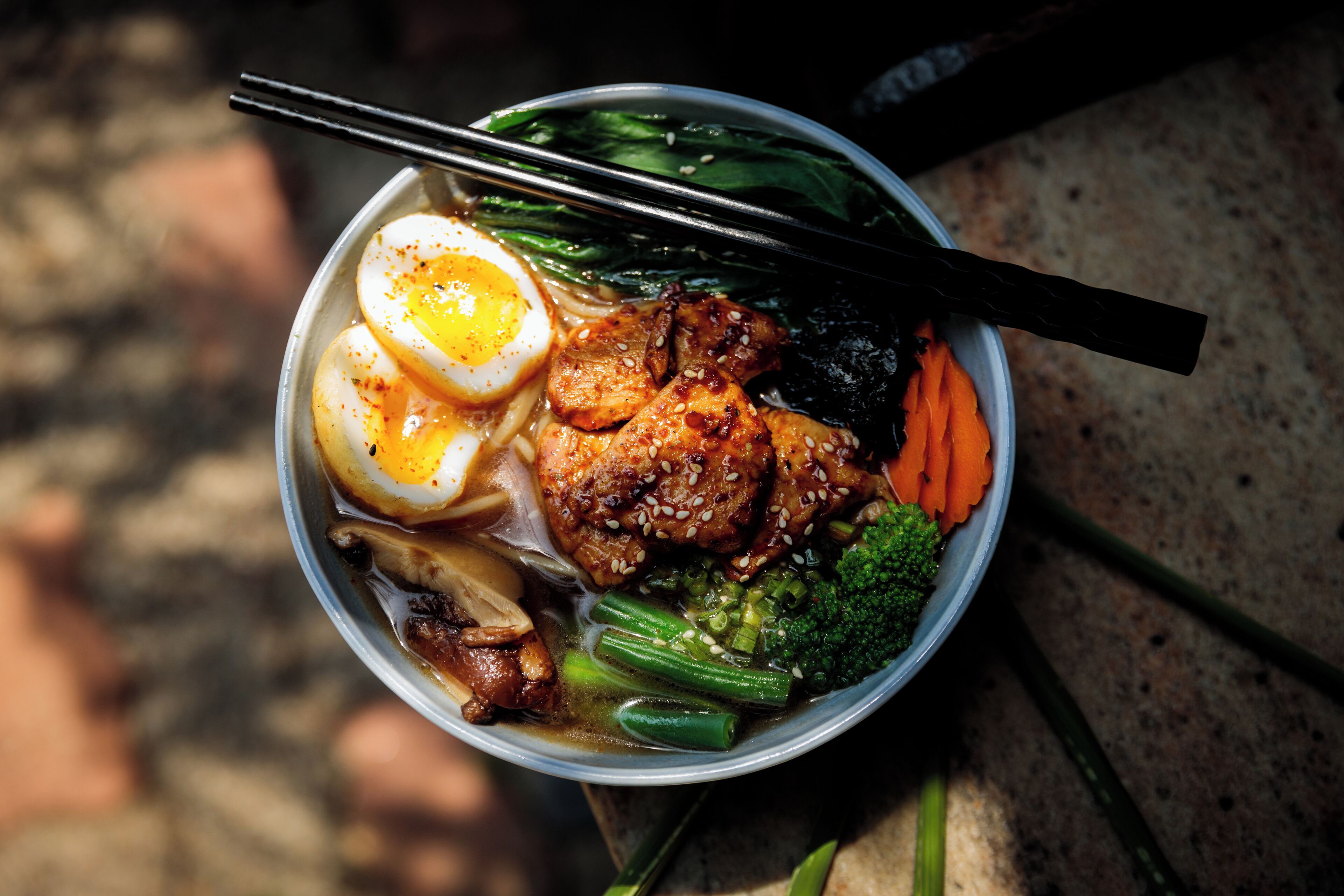Un tazón de comida con diversos ingredientes, como huevos, carne y verduras.
