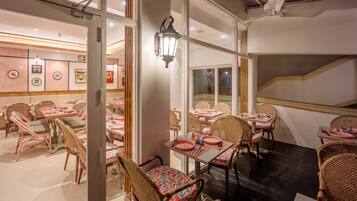 Un restaurante con sillas y mesas de mimbre, una escalera y vistas al exterior.