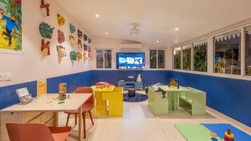 Un cuarto de juegos infantil, lleno de color, con televisor, juguetes y material educativo.