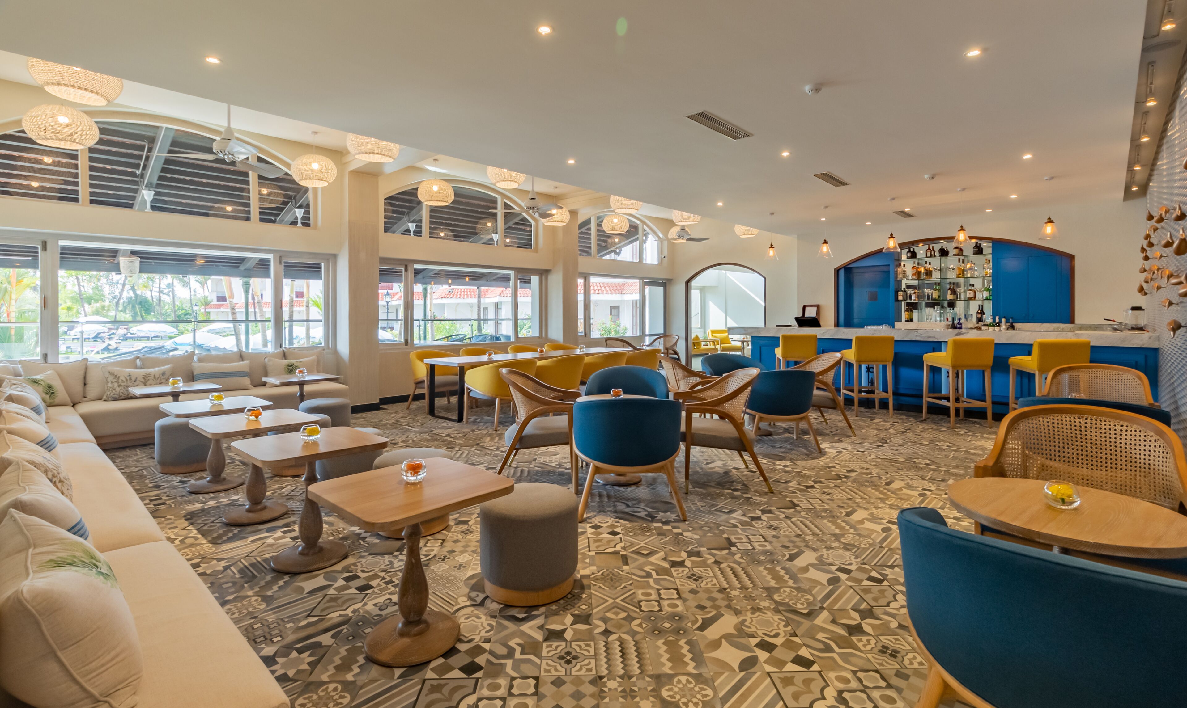 A modern bar area with seating, a patterned floor, and large windows.
