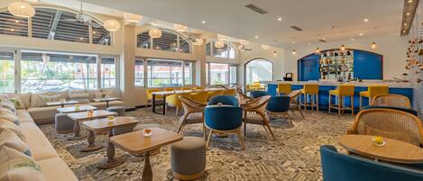 A modern bar area with seating, a patterned floor, and large windows.