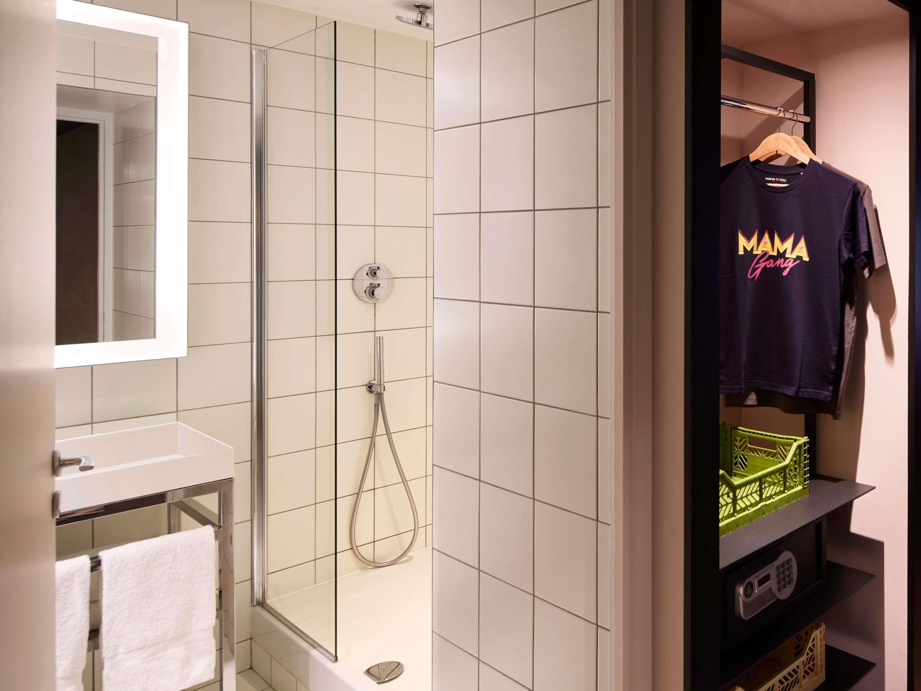 Un baño con ducha envuelta en vidrio, un lavamanos blanco y un espejo.