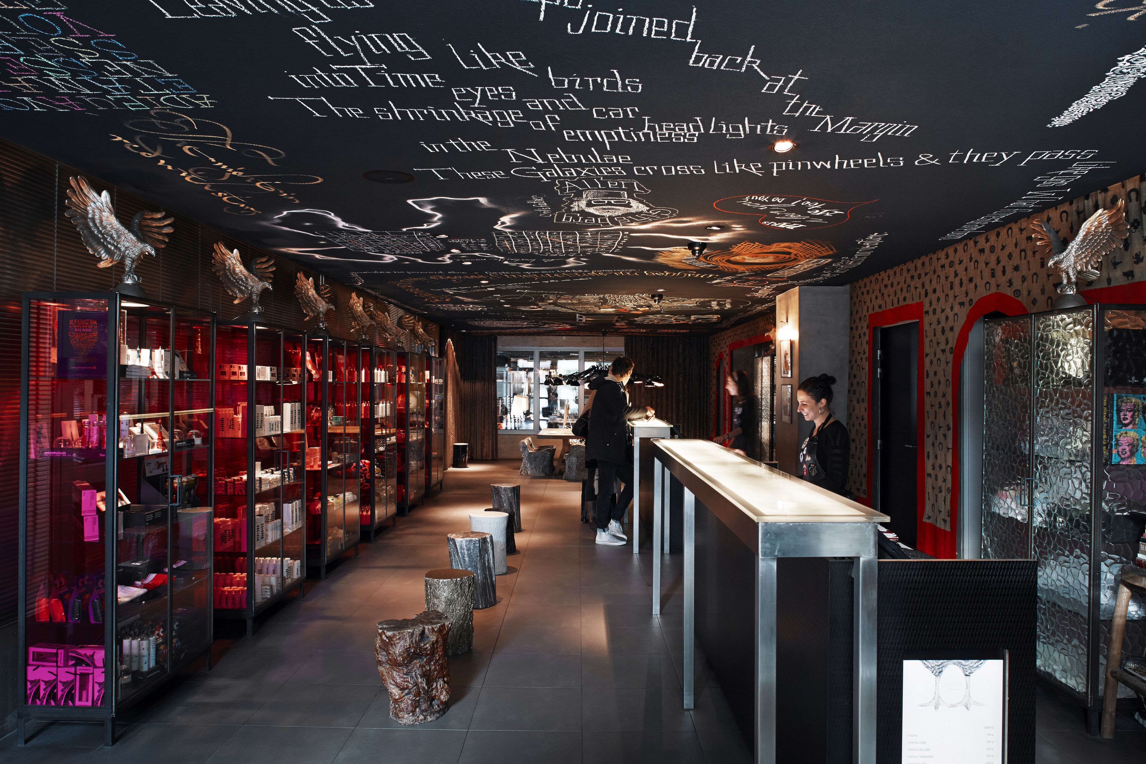 A modern interior with a central counter, glass display cases, and a ceiling with artistic text and designs.