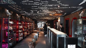 Un intérieur moderne avec un comptoir central, des vitrines et un plafond orné de motifs et d’inscriptions artistiques.