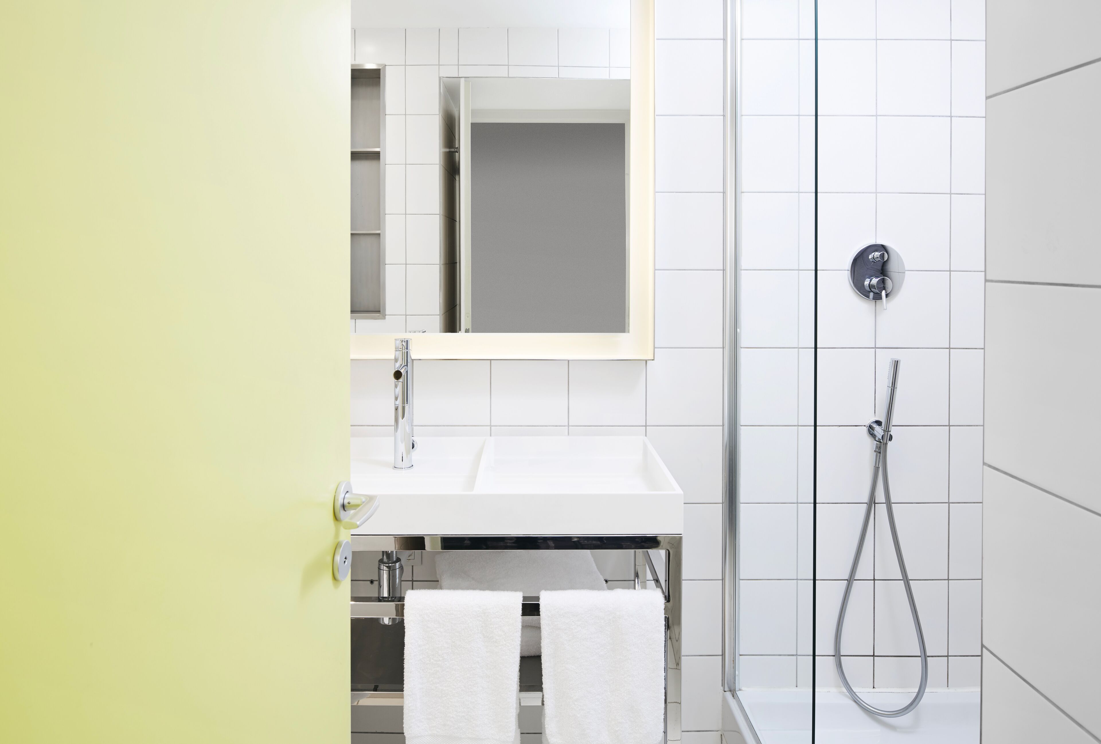A modern bathroom with a white sink, mirror, and shower.