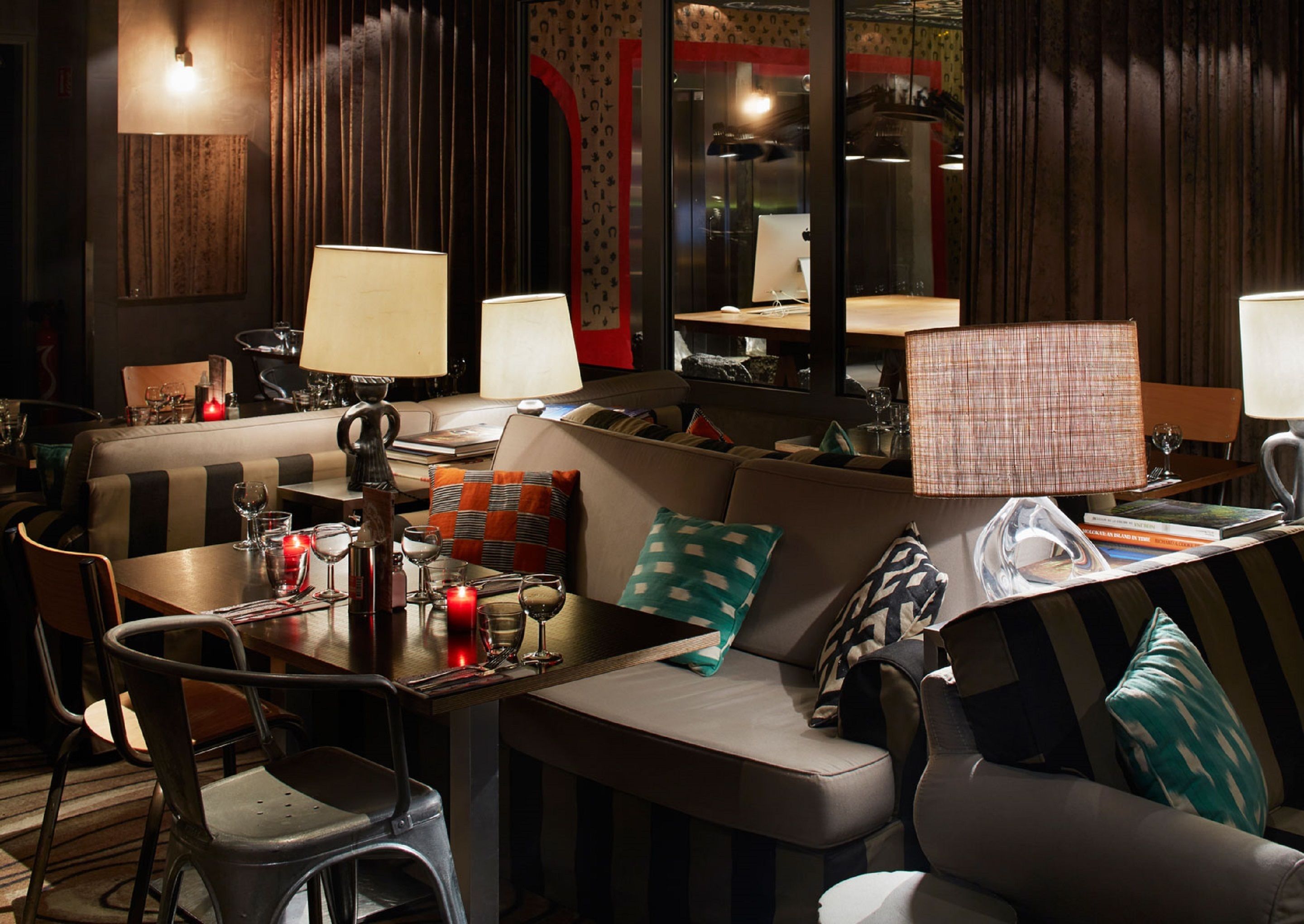 Un restaurant accueillant proposant différents types de sièges, notamment un coin bar, une table à manger avec des chaises et un canapé avec des coussins.
