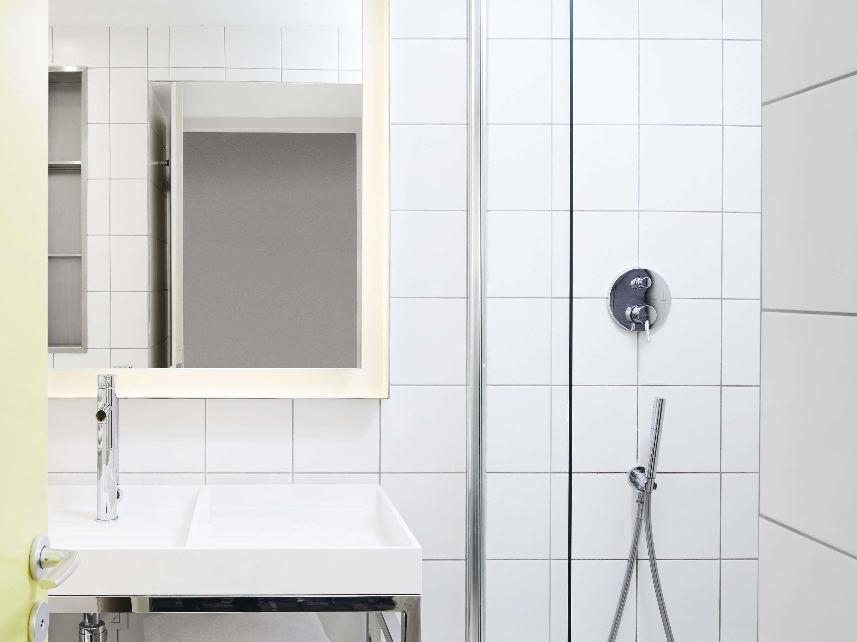 A modern bathroom with a white sink, mirror, and shower enclosure.