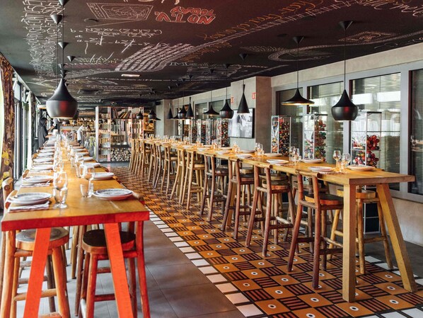 A long dining table with chairs, overhead lighting, and patterned floor tiles. - Mama Shelter Paris East (Paris)