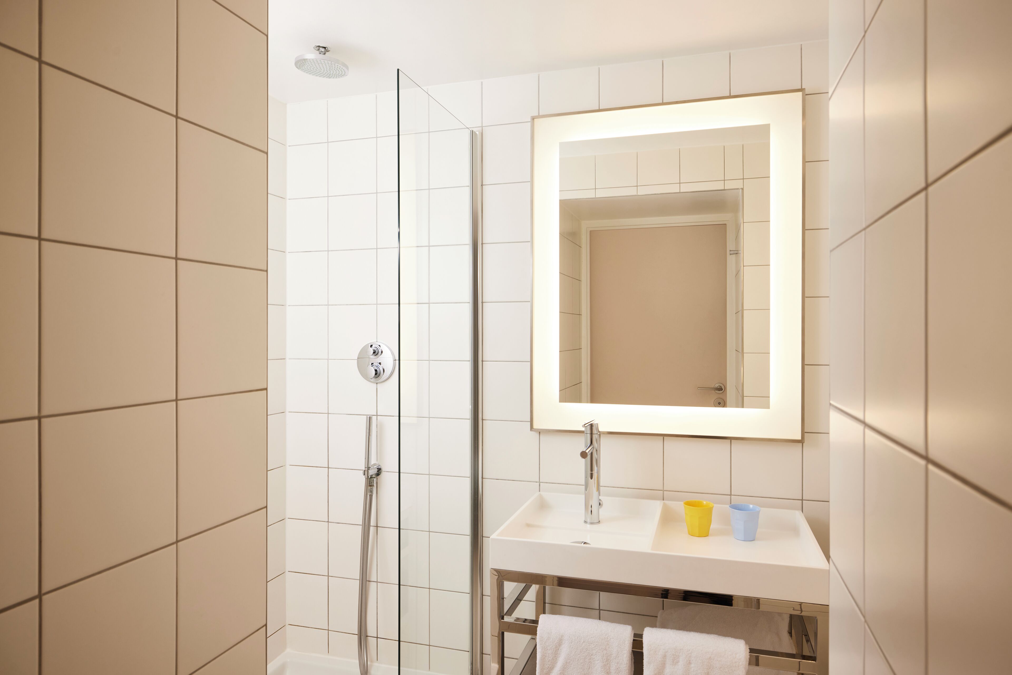 A modern bathroom with a glass-enclosed shower, a white sink with a mirror, and a towel rack.