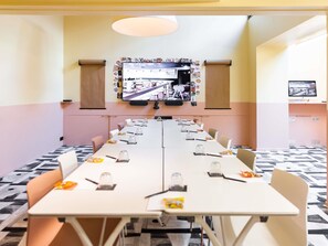A conference room with a long table, chairs, a television screen, and a patterned floor. - Mama Shelter Paris East (Paris)