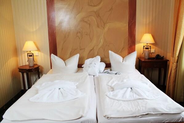 A hotel room with a large bed, two bedside tables with lamps, and a marble-patterned wall. - Hotel Harmonie (Waren (Müritz))