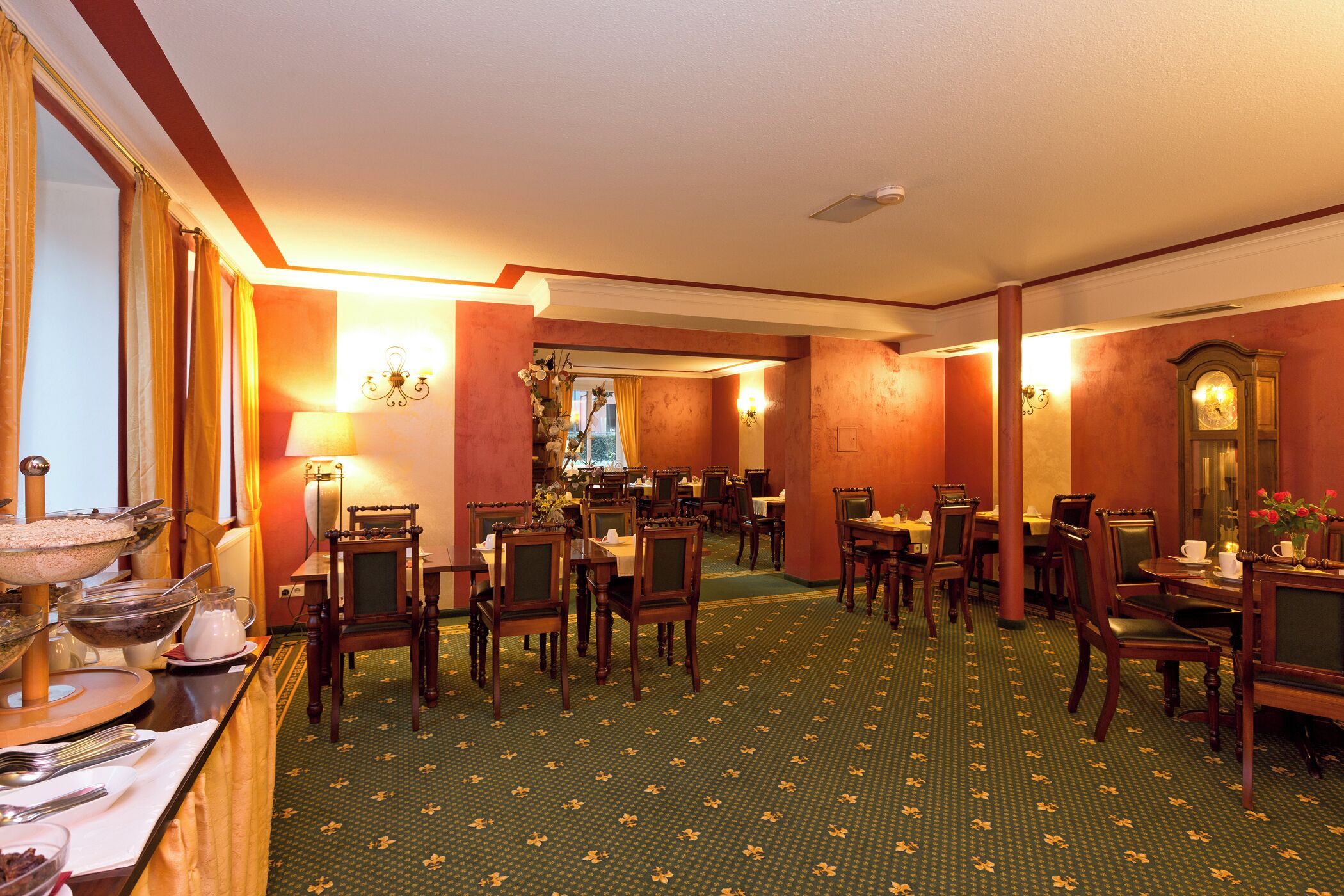 Un comedor de hotel con varias mesas y sillas, un bufé y una araña.
