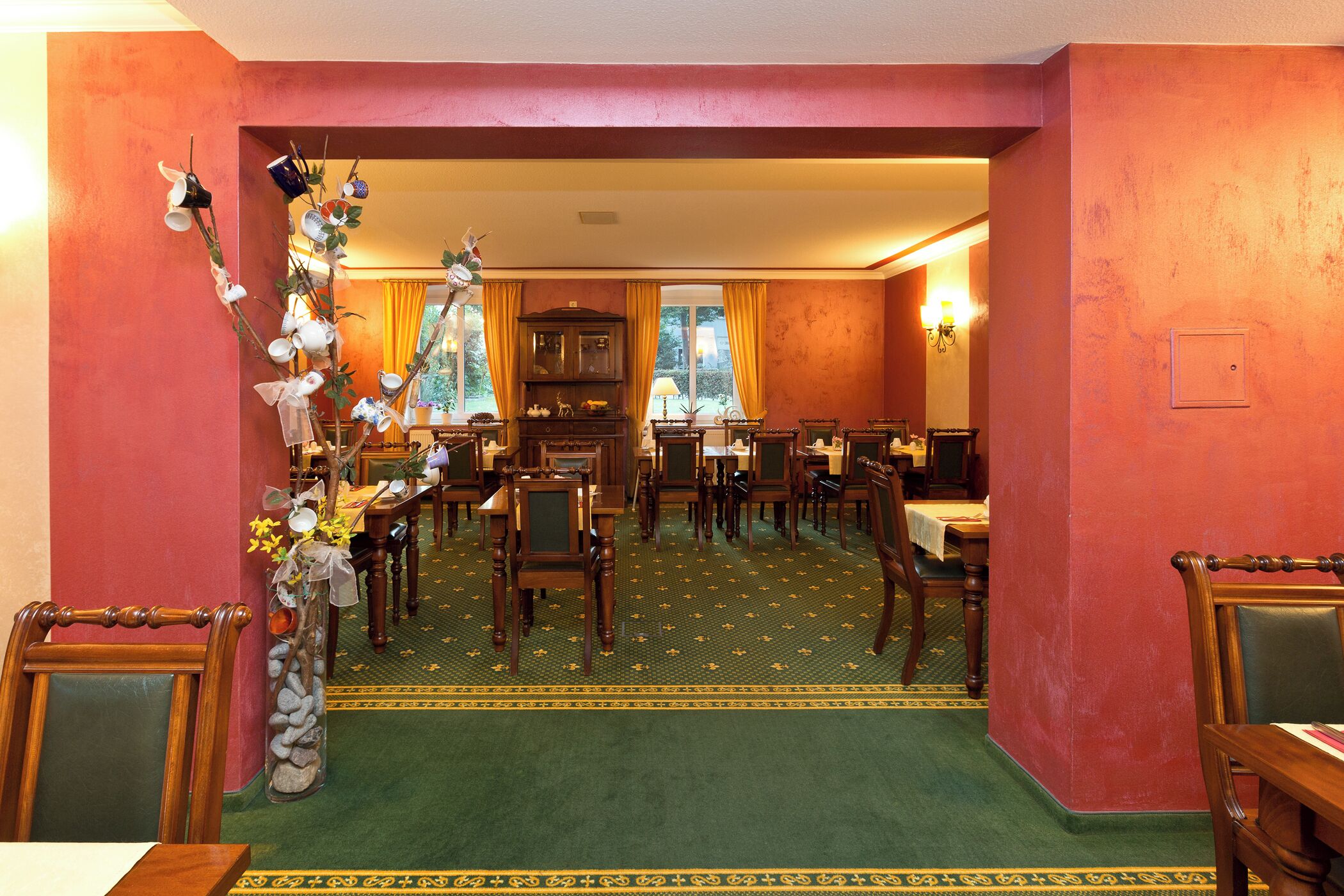Un coin repas avec des meubles en bois, une moquette verte et un mur rouge.