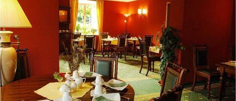 A dining area with multiple tables set for meals, a lamp, and a view of the outdoors.