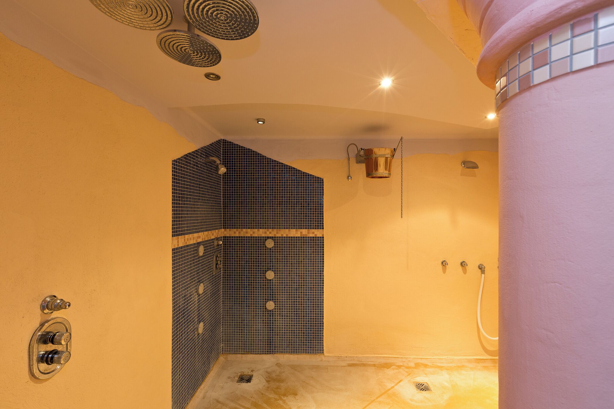 A bathroom with a tiled shower area, a sink, and a toilet.