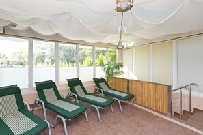 A sunroom with four green lounge chairs, large windows, and a bamboo wall.