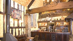 A rustic interior with a stone fireplace, wooden beams, a bar area, and a patterned carpet. - The Horseshoe Inn (Hailsham)