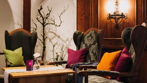 A room with two upholstered chairs, a wooden table, and a wall-mounted light fixture. - Gutshof Sagmuehle (Bad Griesbach im Rottal)