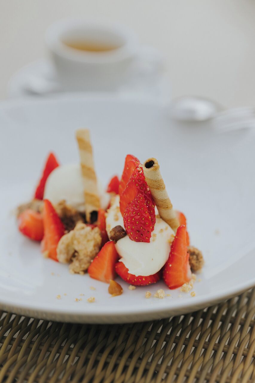 A dessert plate with strawberries, a wafer, and a scoop of ice cream.
