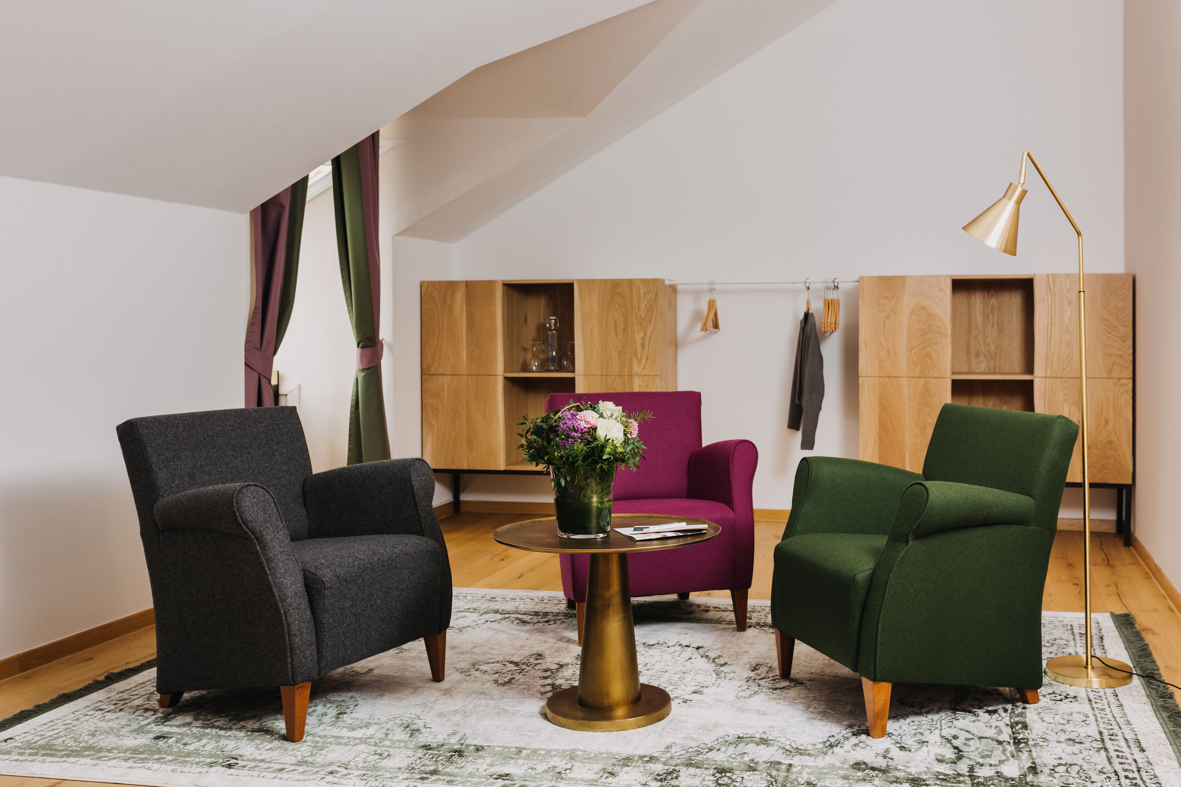 Ein modernes Wohnzimmer mit einem runden goldenen Tisch, zwei Sesseln, einer Stehlampe und einem Holzregal.