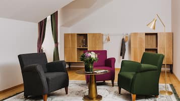 Ein modernes Wohnzimmer mit einem runden goldenen Tisch, zwei Sesseln, einer Stehlampe und einem Holzregal.