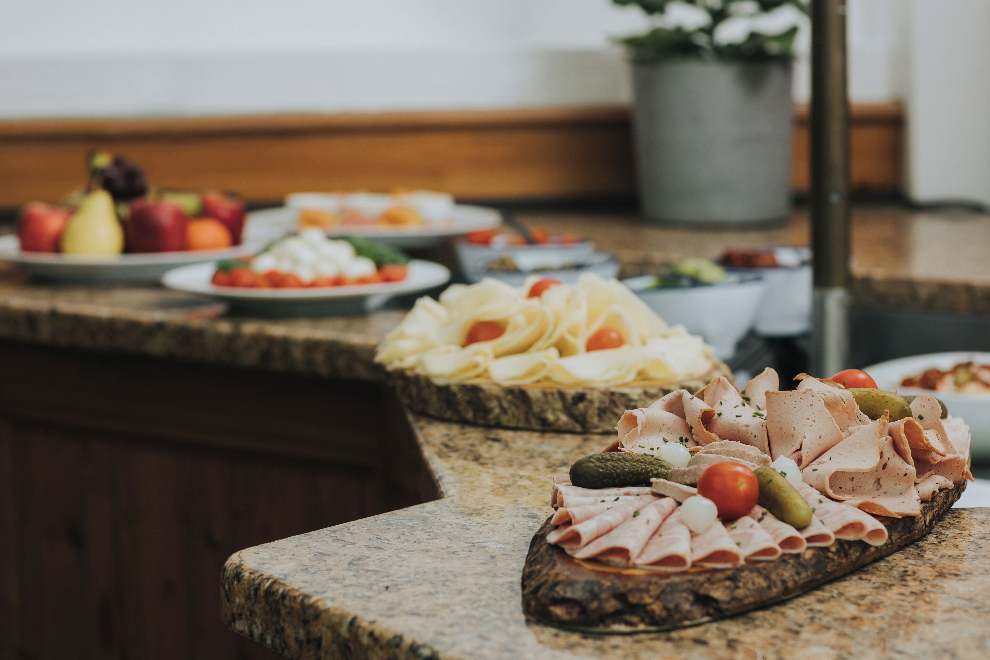 A buffet table with various food items including sliced meats, cheeses, and vegetables.