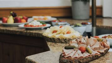 Een buffettafel met verschillende soorten eten, zoals vleesschotels, kazen en groenten.