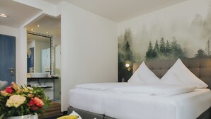 A modern hotel room with a bed, a dining area, and a bathroom. - Gutshof Sagmuehle (Bad Griesbach im Rottal)