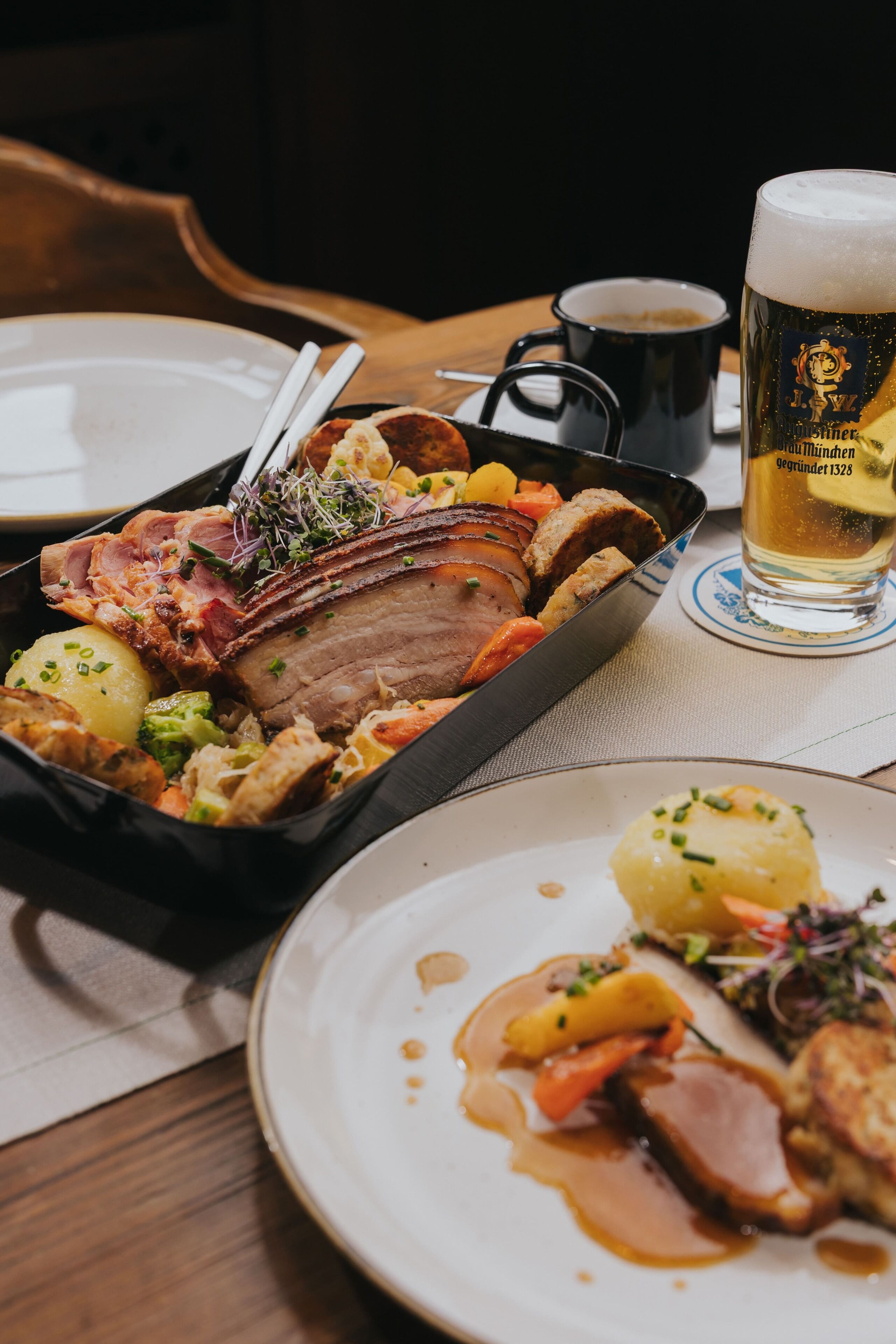 Un repas composé de viande rôtie, de légumes et d’un verre de bière, le tout servi sur une table.