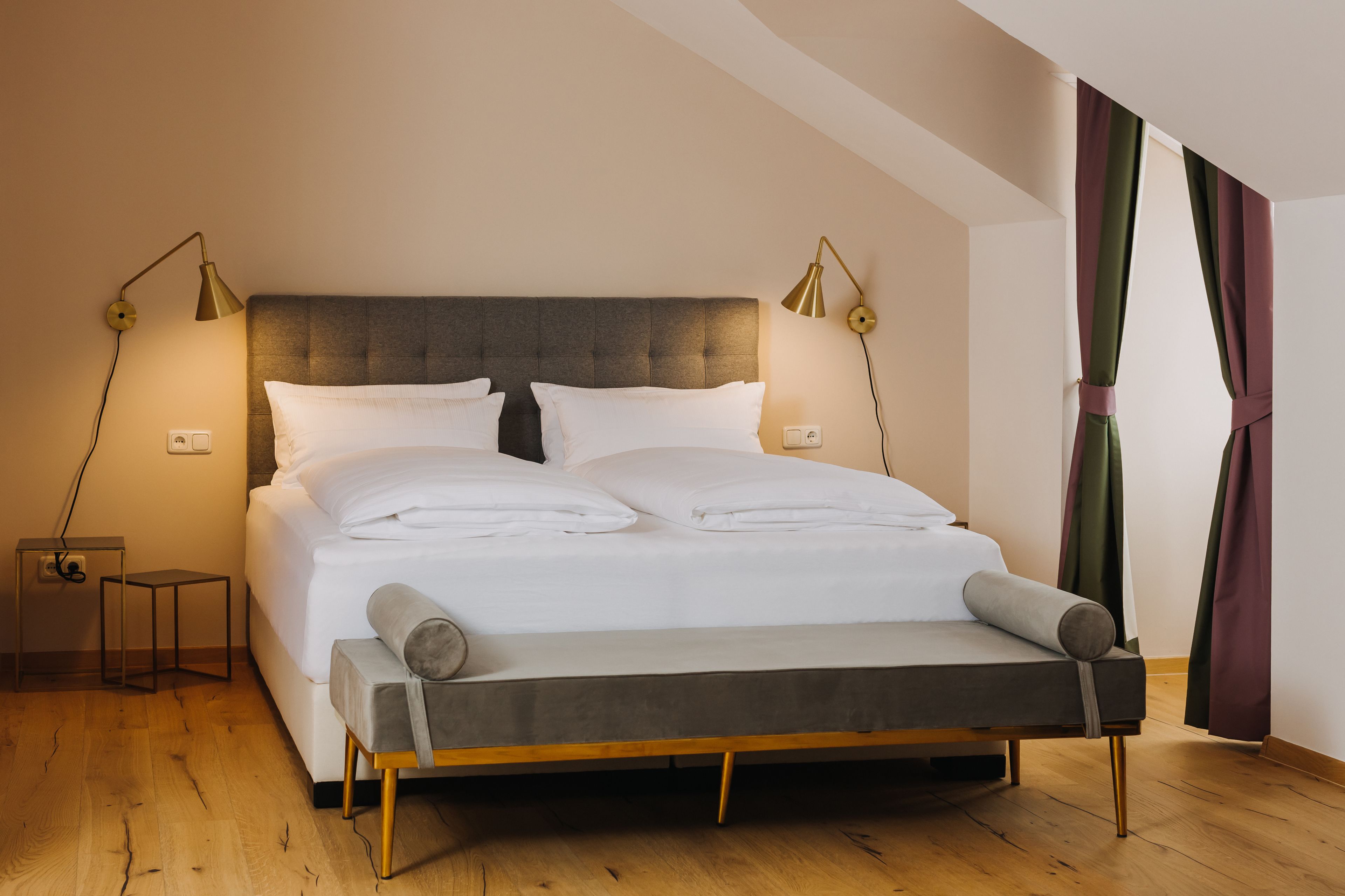 Ein modernes Schlafzimmer mit einem großen Bett, Nachttischlampen und einer Bank.