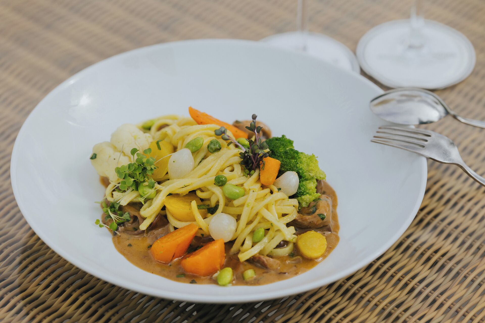 A plate of food with vegetables and noodles on a white plate.