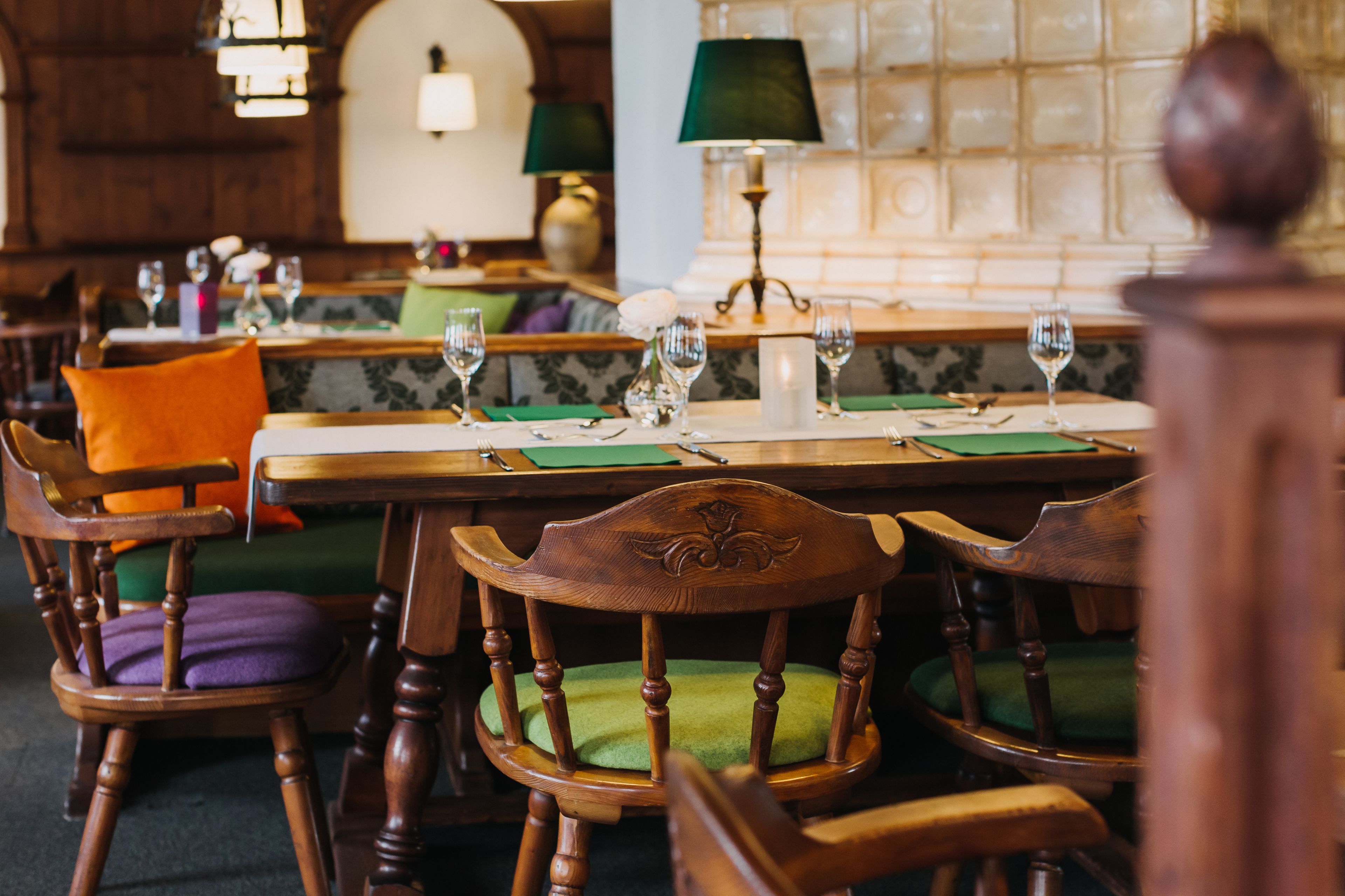 L'intérieur d'un restaurant avec des tables et des chaises en bois, ainsi que des sièges rembourrés de couleur verte.